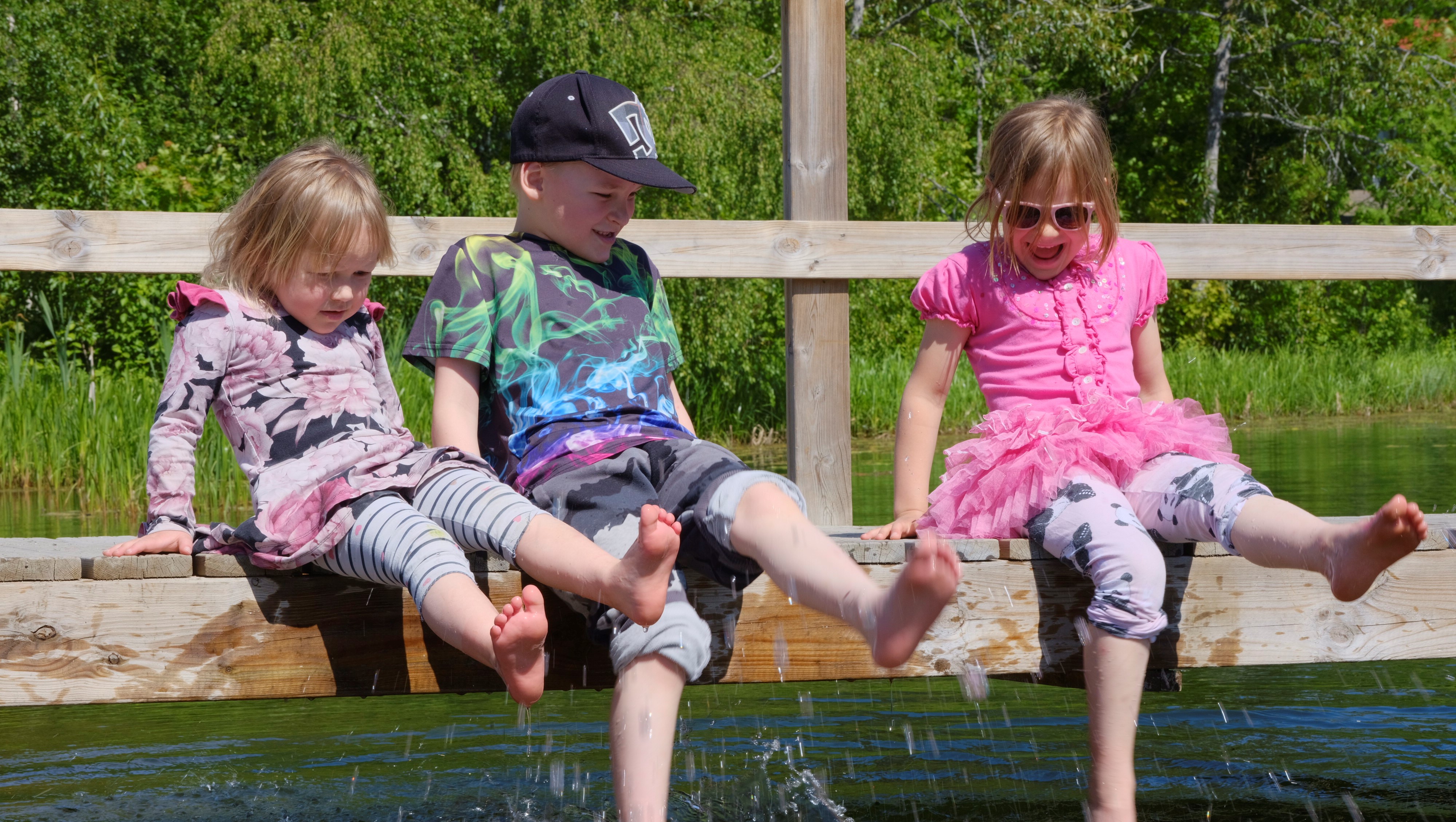 Lapset polskivat vettä laiturilla.