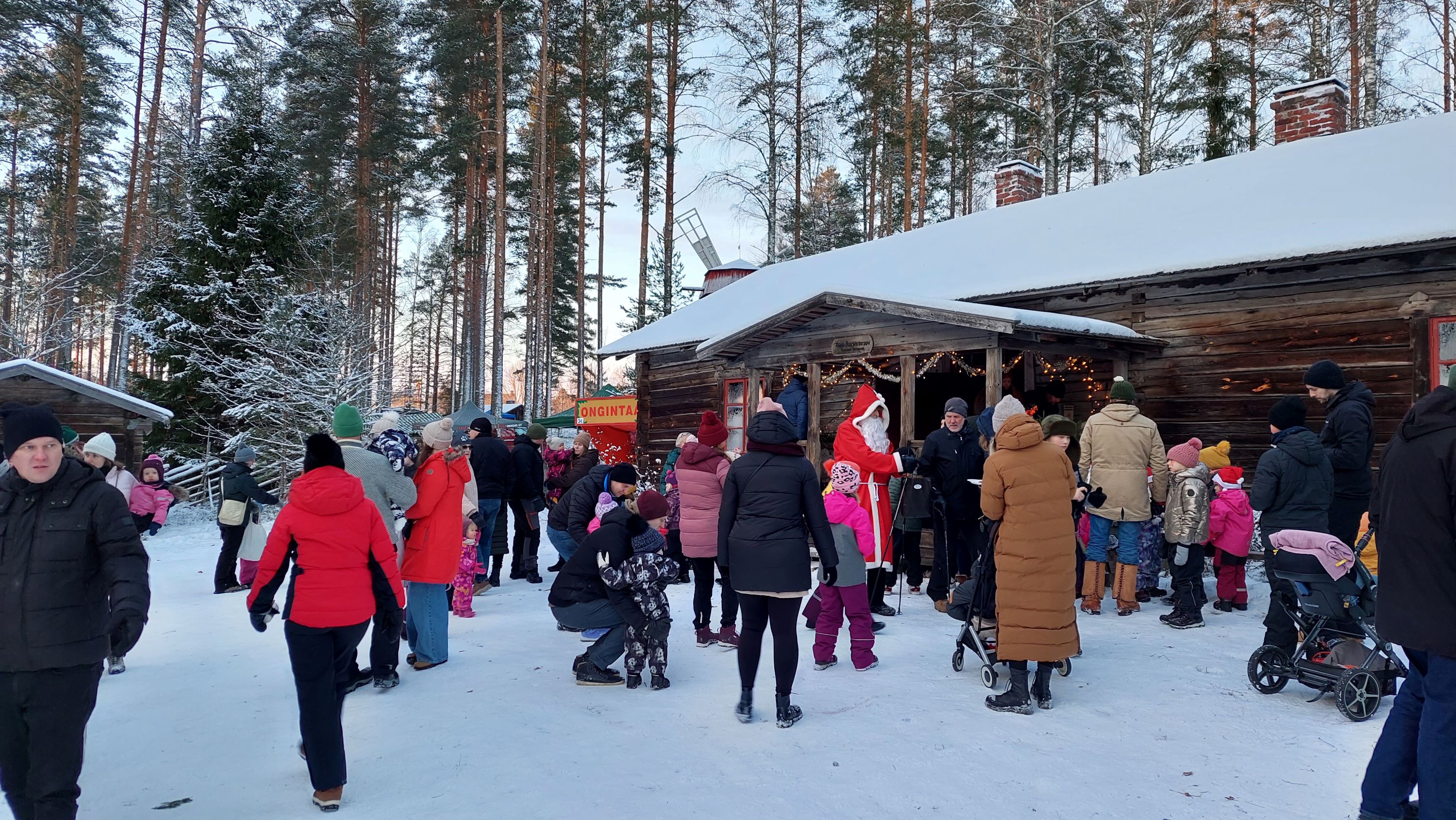 Yleisöä Janakkalan joulunavauksessa lumisella museopihalla.